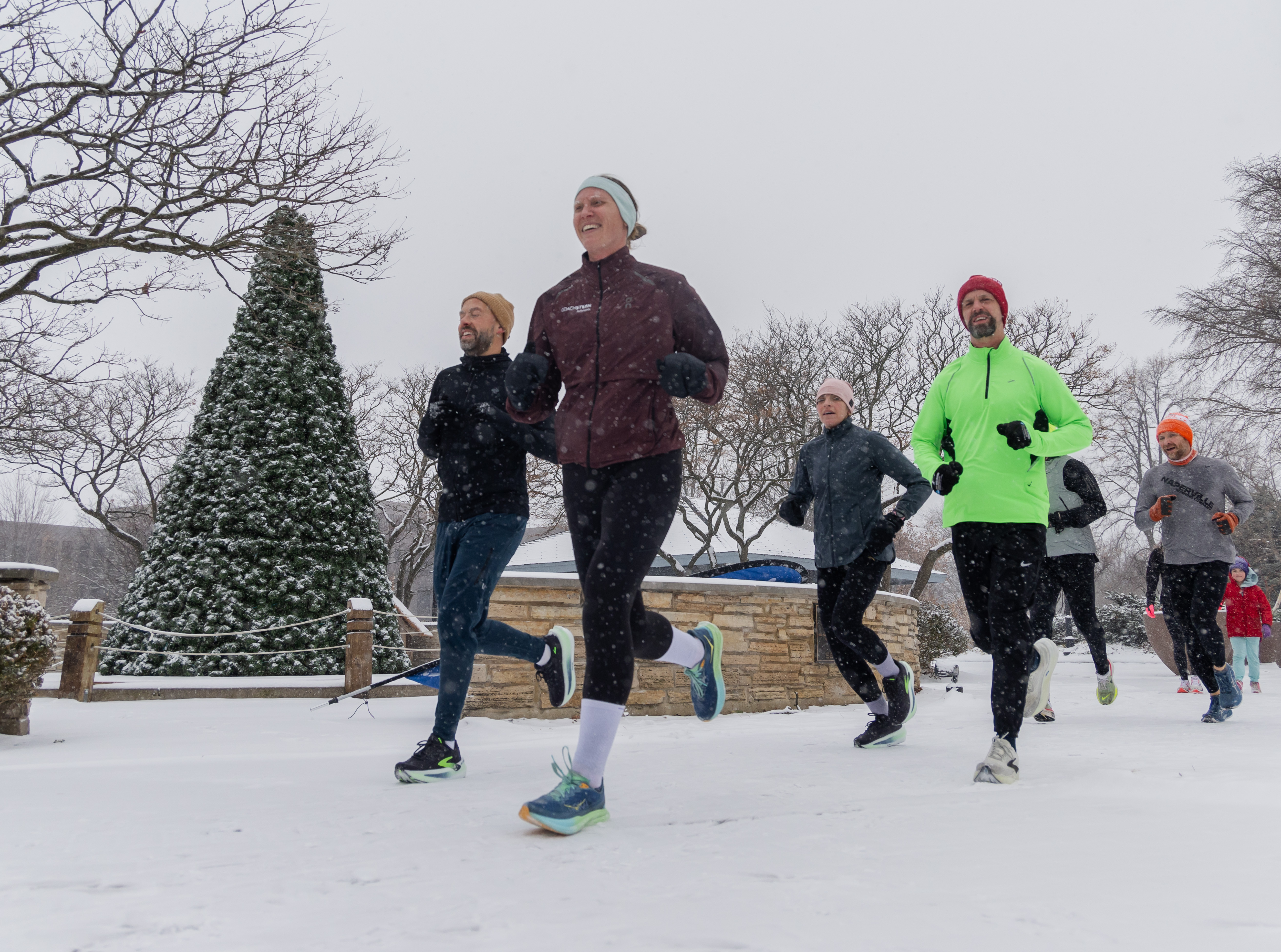 Participants in the Naperville Run Company's "Small Biz Saturday 25th Anniversary Fun Run + Walk" run near the riverwalk on Jackson Avenue during a winter storm on Nov. 29, 2025, in downtown Naperville. (Dominic Di Palermo/Chicago Tribune)