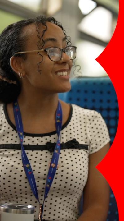 A young woman wearing glasses and a white top with black spots