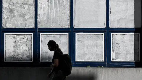 Getty Images A woman walks past the windows of a school, which have been covered in white chalk