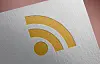 Golden RSS feed icon on a textured white surface.