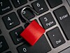Red padlock lying across laptop keyboard keys.