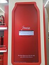 Red Coca-Cola display panel with a warning message about low storage space, shown inside a store.