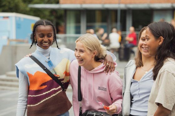 Smilende student leser bok på campus, foto.