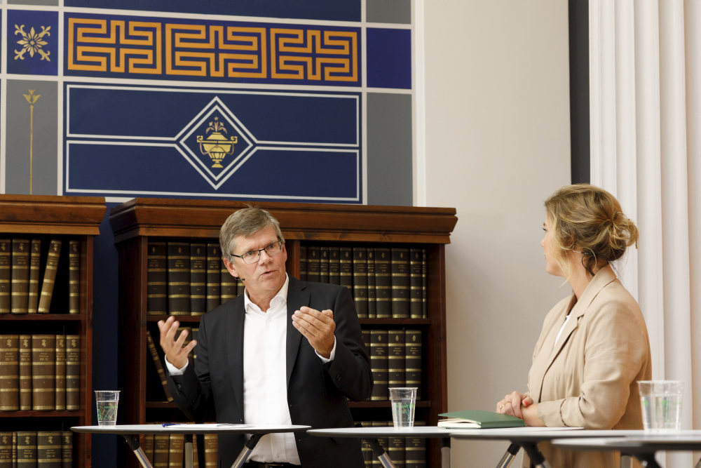 Bildet kan inneholde: mikrofon, frakk, gest, talsperson, dress.