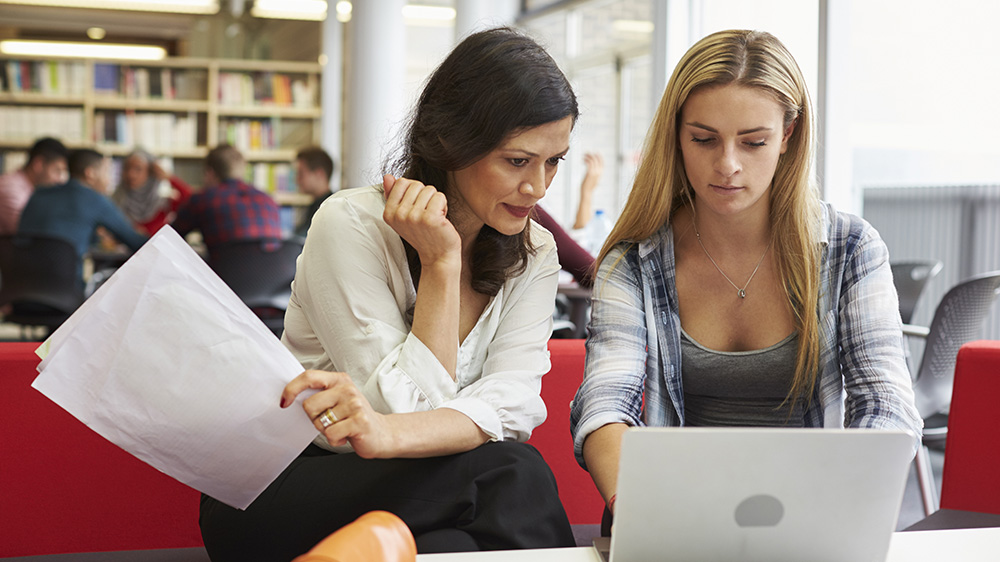 Bilde av to personer med en bærbar PC i et bibliotek.