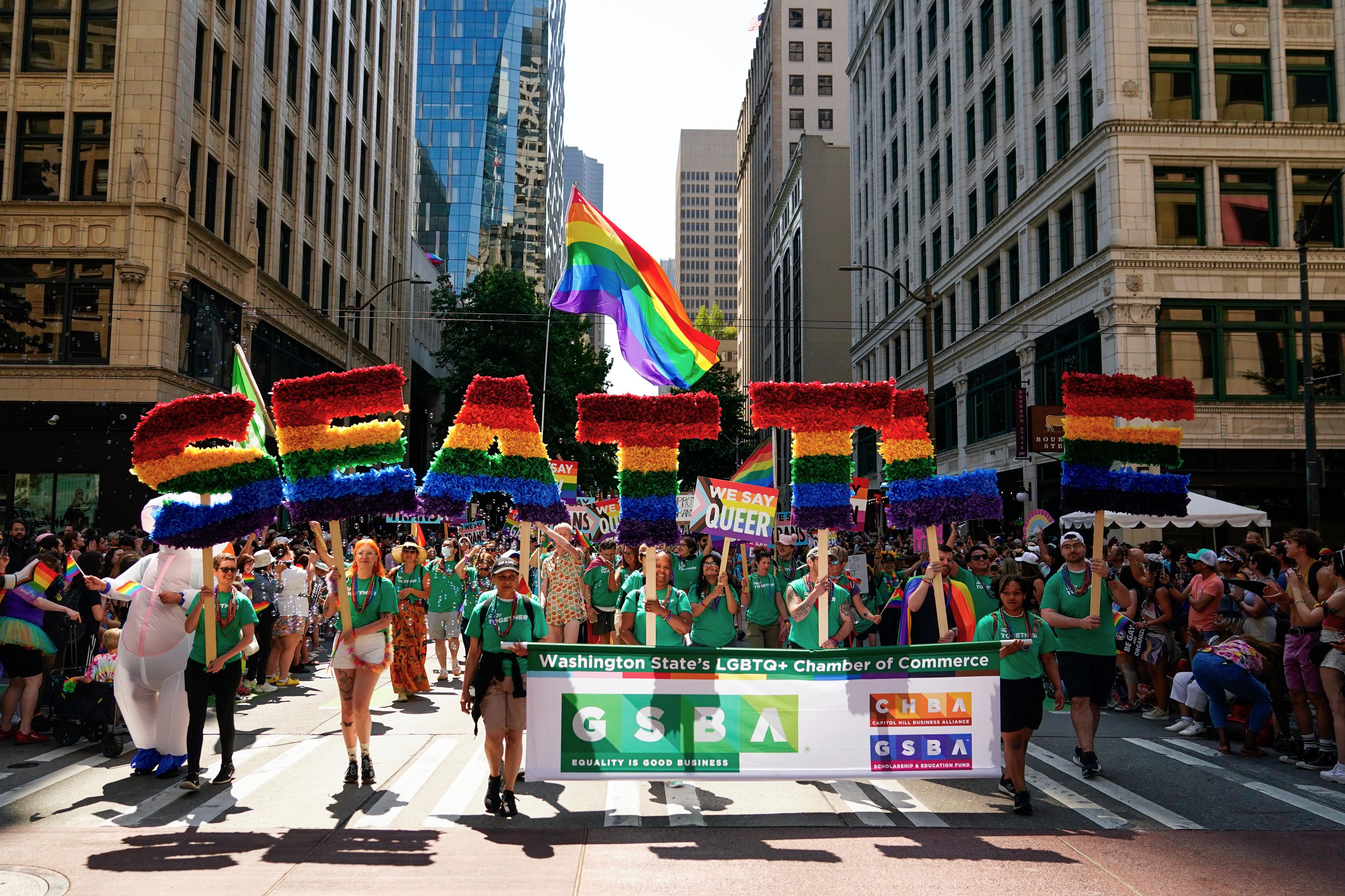 Marchers with the Greater Seattle Business Association, Washington's LGBTQ+ and allied chamber of commerce, hold rainbow letters spelling out "Seattle" during the annual Seattle Pride Parade on June 25, 2023. (AP Photo/Lindsey Wasson)