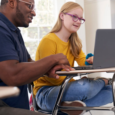 Un bărbat și o femeie stând la un birou și uitându-se la un laptop.