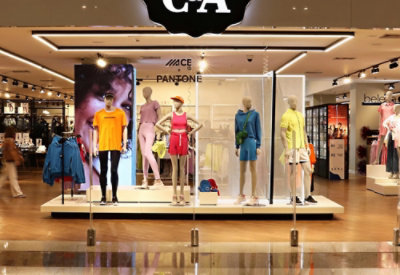 Storefront with six mannequins dressed in colorful outfits, set against a brightly lit fashion retail display.