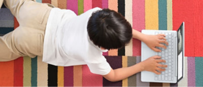 O persoană lucrează la laptop pe covor.