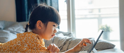 Uma criança a olhar para um tablet.