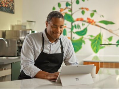Мъж в престилка използва таблет Microsoft Surface.