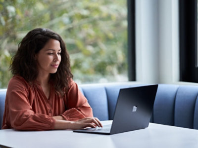 O persoană care stă la masă și utilizează un computer