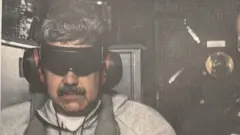 Rostro de Nicolás Maduro con anteojeras y protectores auditivos. Viste una camiseta blanca y un conjunto deportivo gris.