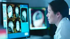 Scientist looking at 3D rendered graphic scans of brains