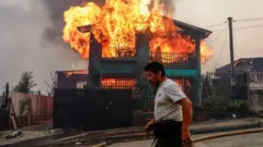 Un hombre pasa caminando junto a un edificio en llamas en la región de Biobío, en Chile.