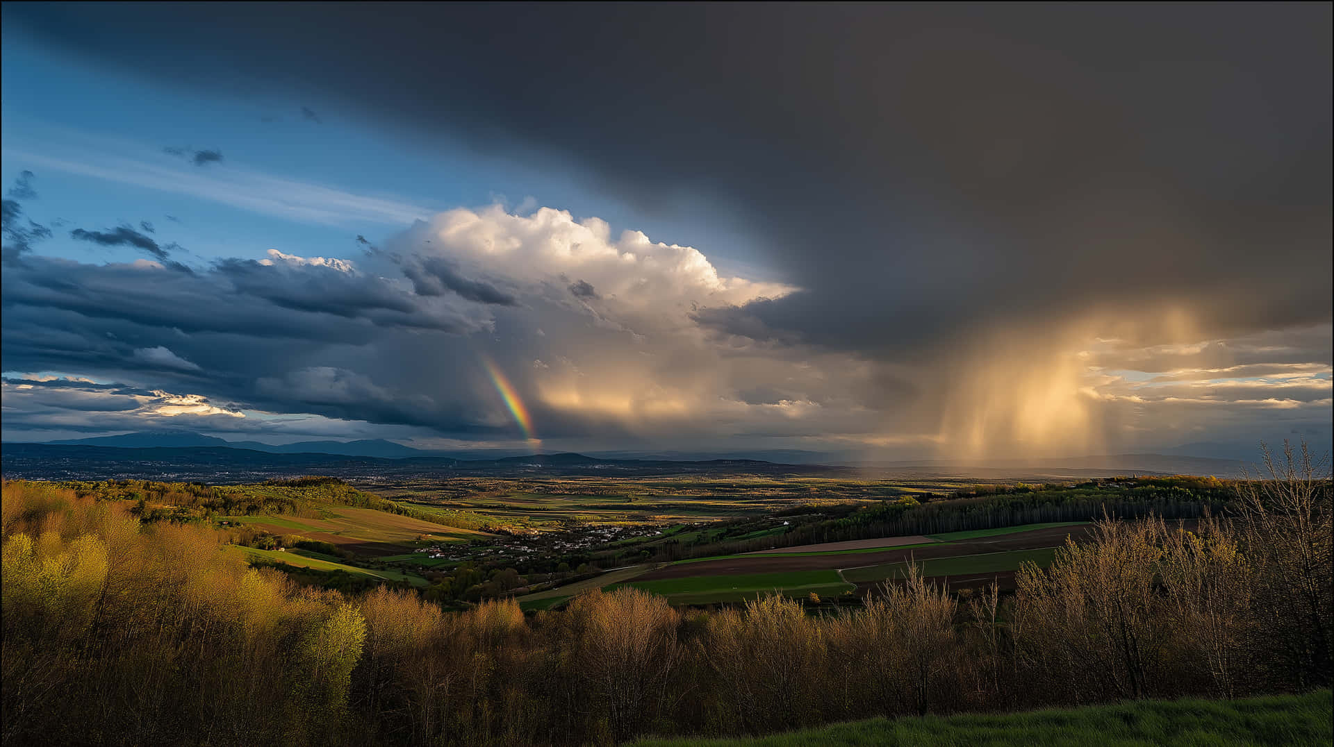 Dramatic Stormy Sky With Rainbow Over Green Landscape Wallpaper