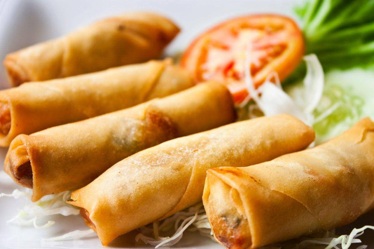 Caption: Authentic Chinese Egg Rolls Artfully Presented with Fresh Vegetables Wallpaper