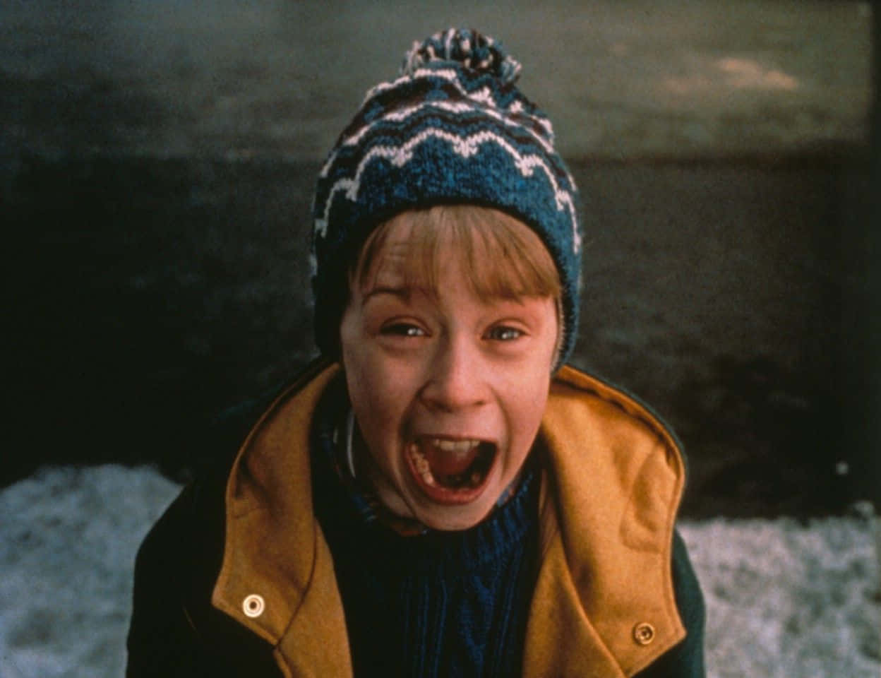 A Boy In A Yellow Jacket And Hat Is Laughing