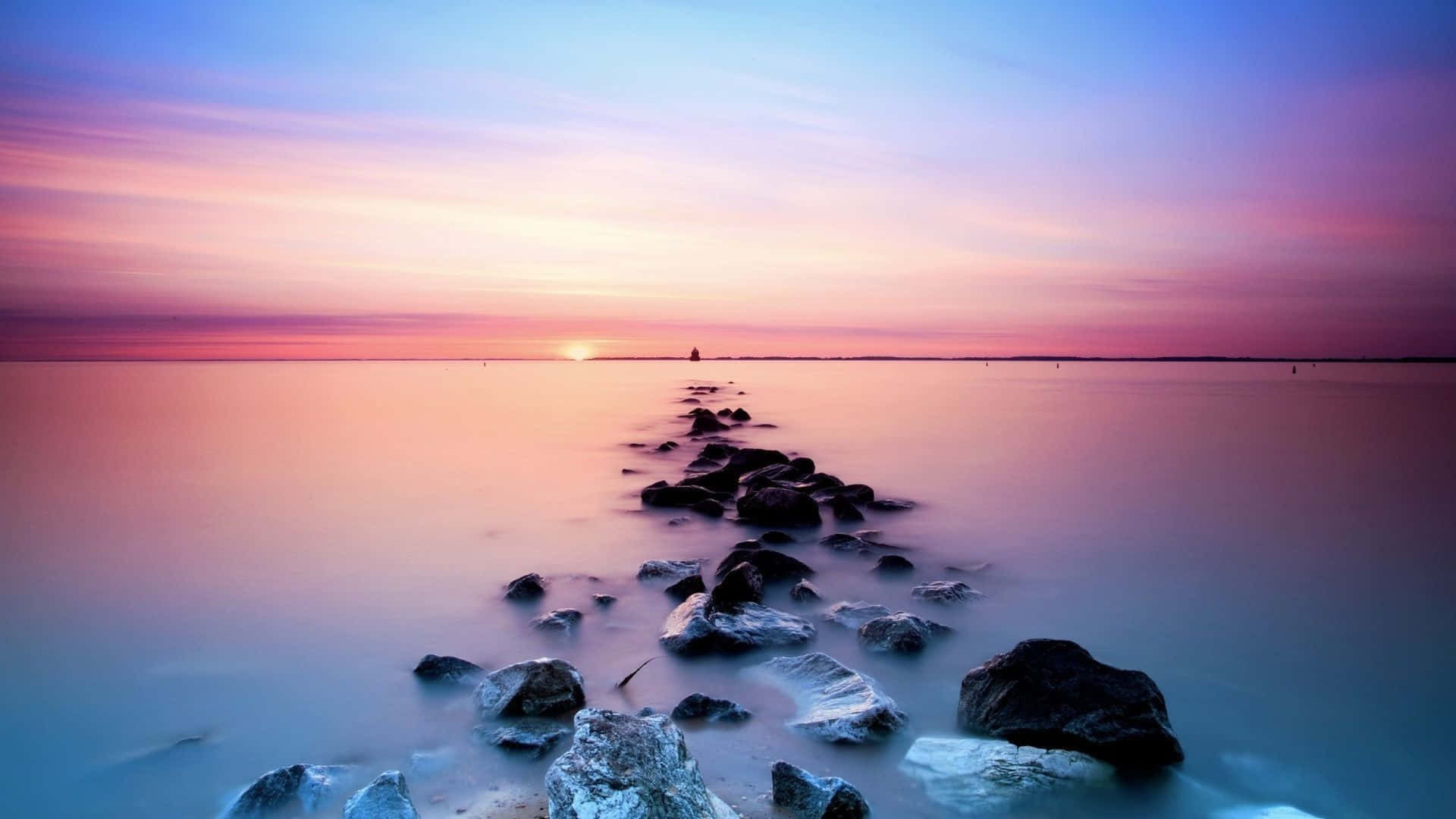 A Rock Line With A Sunset Over The Water