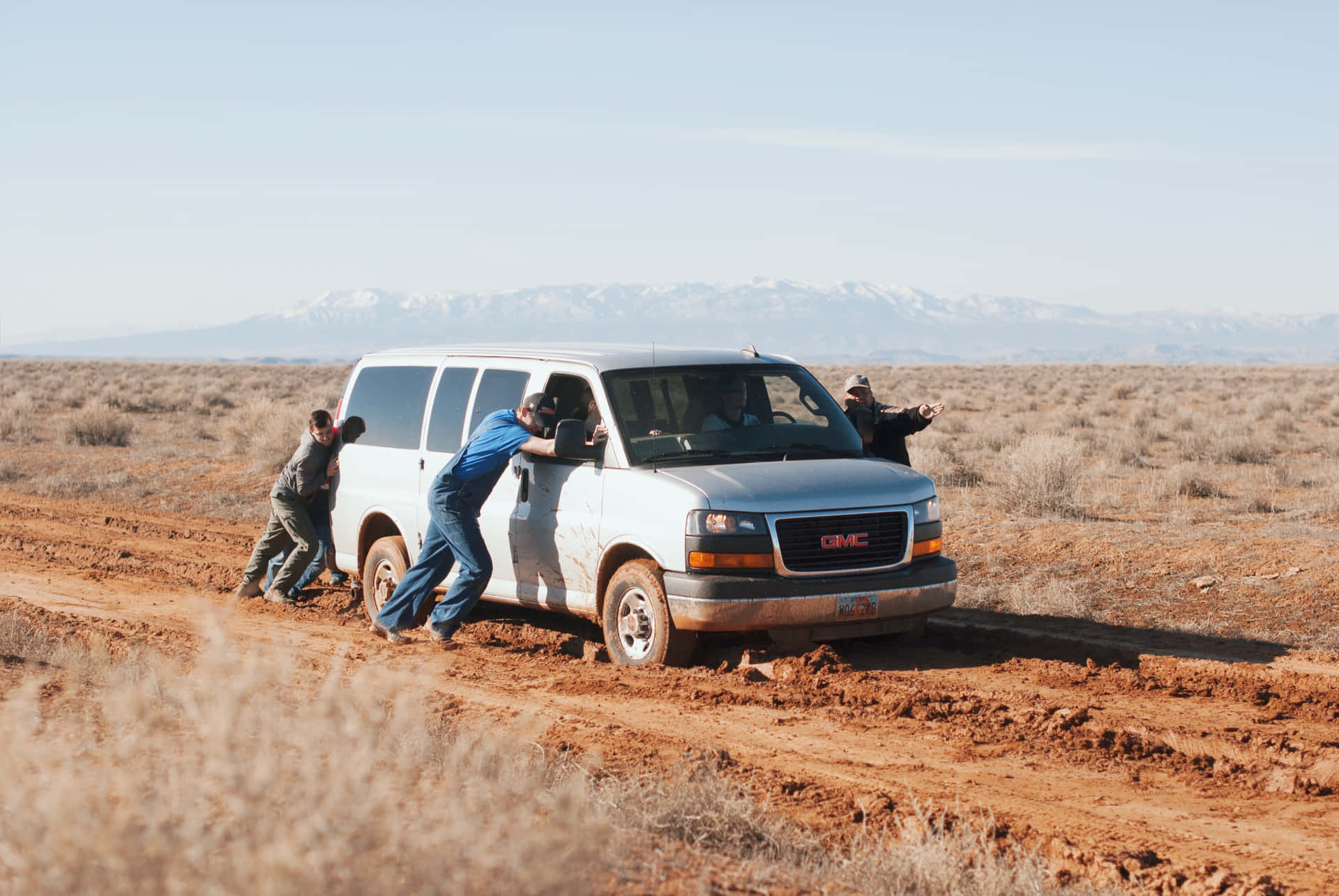 Teamwork in Adversity - Men Pushing a Stranded Car Wallpaper