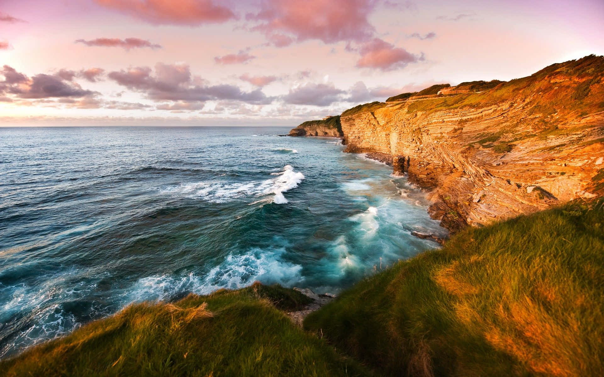 A Majestic Coastal Scene under a Pink-Clouded Sky Wallpaper